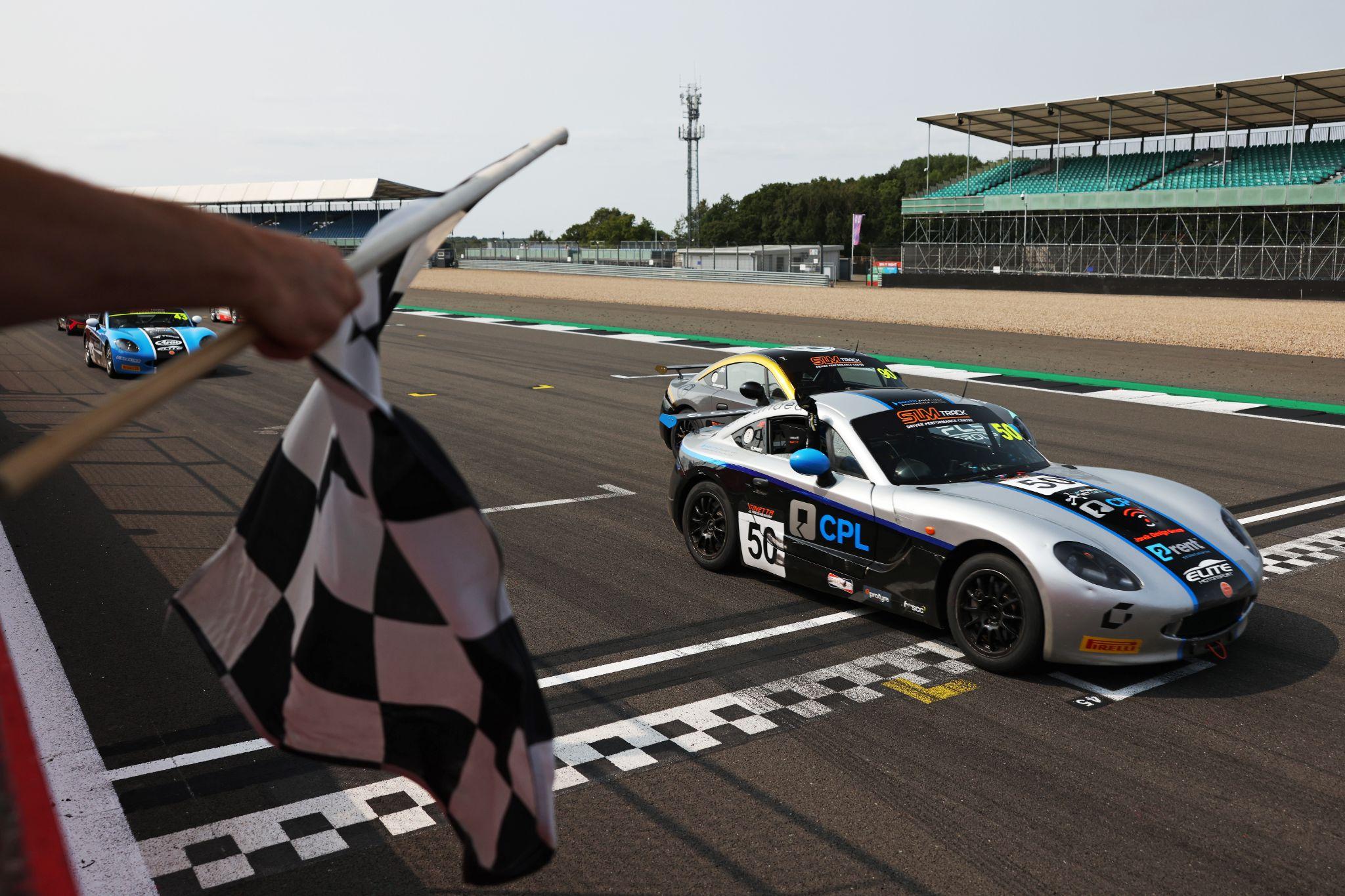 Racing cars on the start line with a chequered flag in the foreground